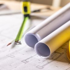 Extension plans, tape measure and yellow hard hat laid out on a table