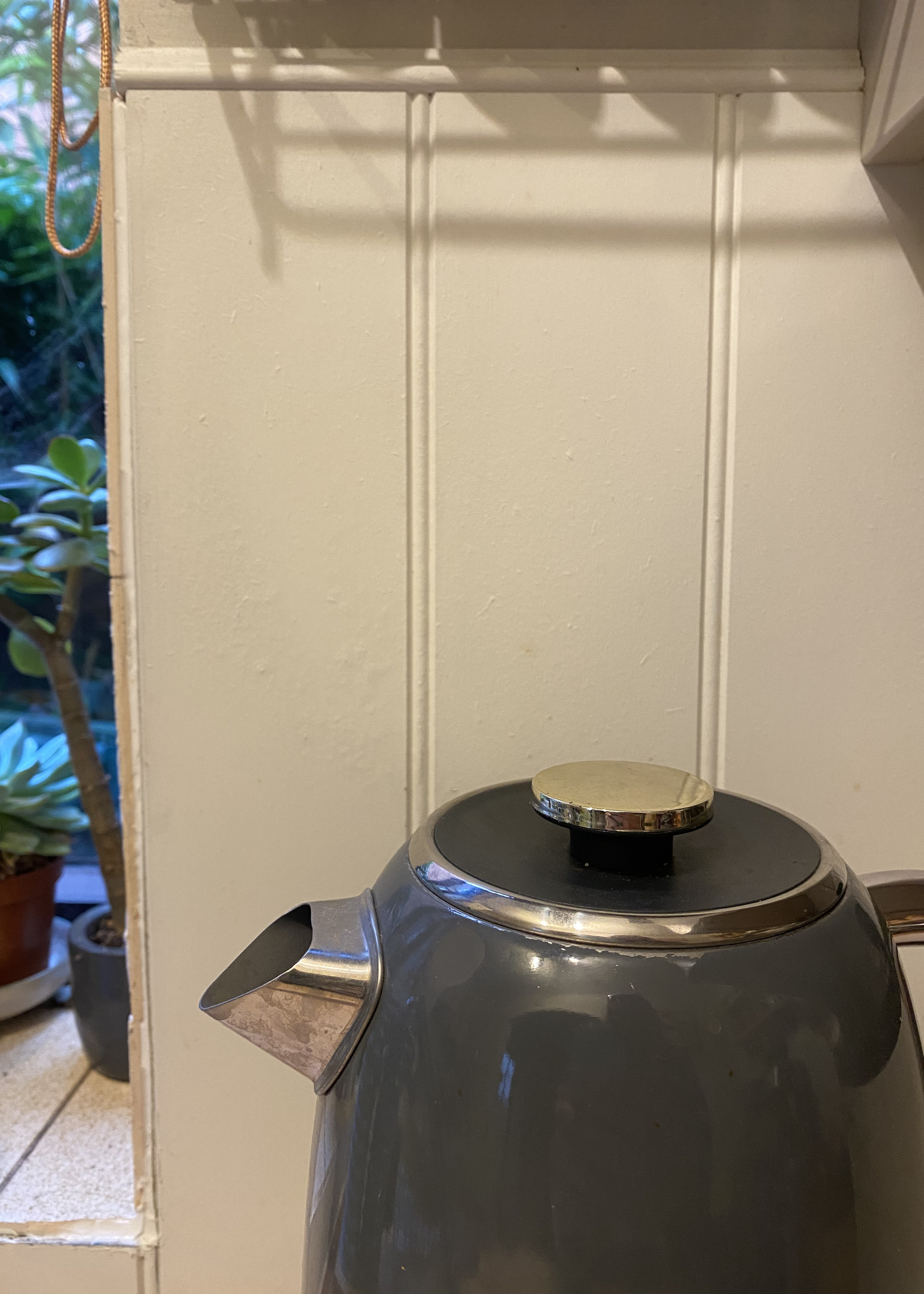 A close up of a kettle and a panelled backsplash with a bubbled texture