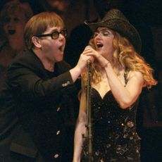Elton John and Madonna in black outfits performing at the Rain Forest Concert at Carnegie Hall in 1998