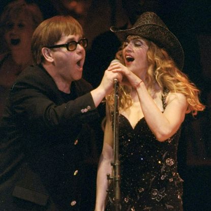 Elton John and Madonna in black outfits performing at the Rain Forest Concert at Carnegie Hall in 1998