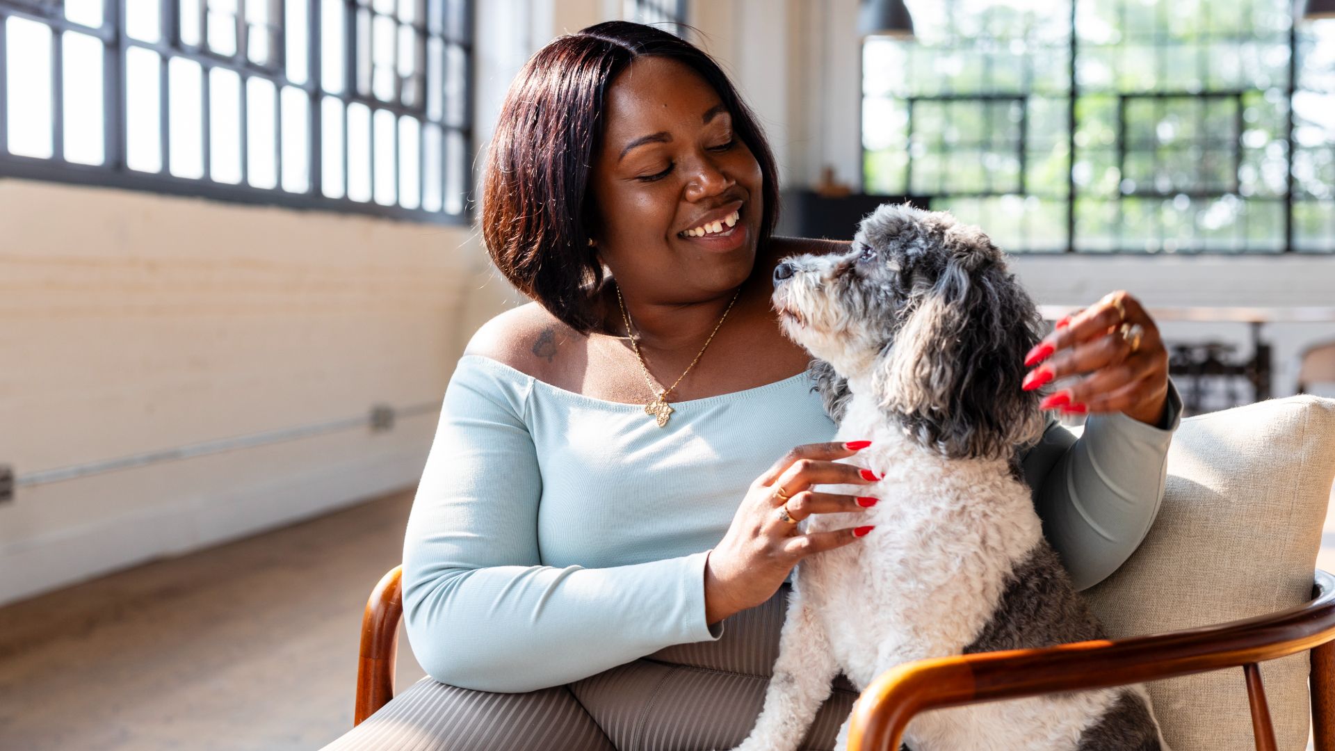 Woman sits with and fusses a dog