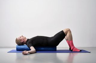 Male cyclist using a foam roller to ease his shoulder pain from cycling