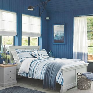 Blue bedroom with wall panelling and white wooden bed