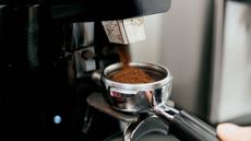 How to grind coffee: an automatic coffee grinder dispensing finely ground coffee into a portafilter