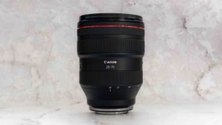 Canon RF 28-70mm f2 L USM Lens standing vertical against a marble backdrop