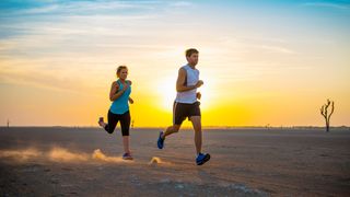 Man and woman running in desert at sunrise