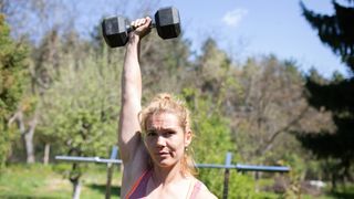 Woman holds dumbbell above her head