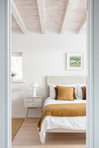 A white toned bedroom with yellow cushions