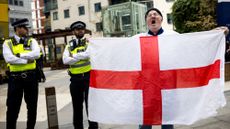 A man holds an England flag next to two police officers