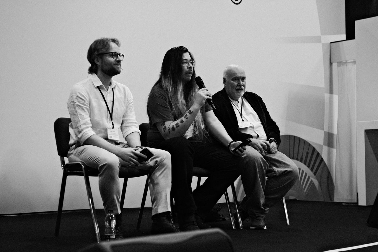 Three speakers seated onstage during a panel discussion
