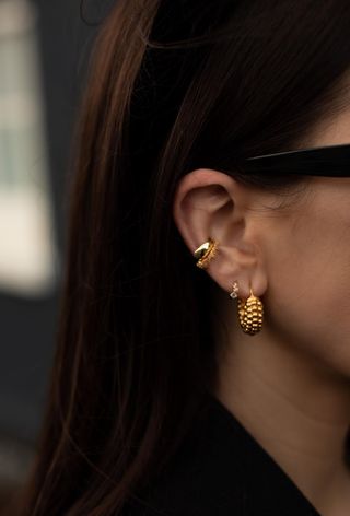 a photo of a woman's ear with gold earrings for double piercings