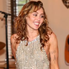 Miley Cyrus wearing a sparkly dress during a private performance.