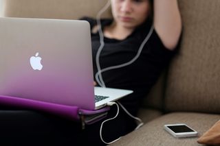 Woman on a Mac and using earbuds