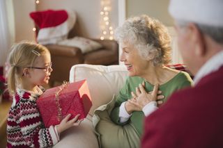 Young girl giving gift to grandparents