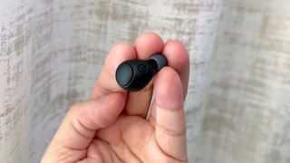 Sony WF-C700N earbuds held in finger tips to show size
