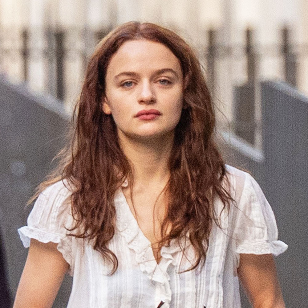 Joey King wearing white ruffle top, jeans, and sandals