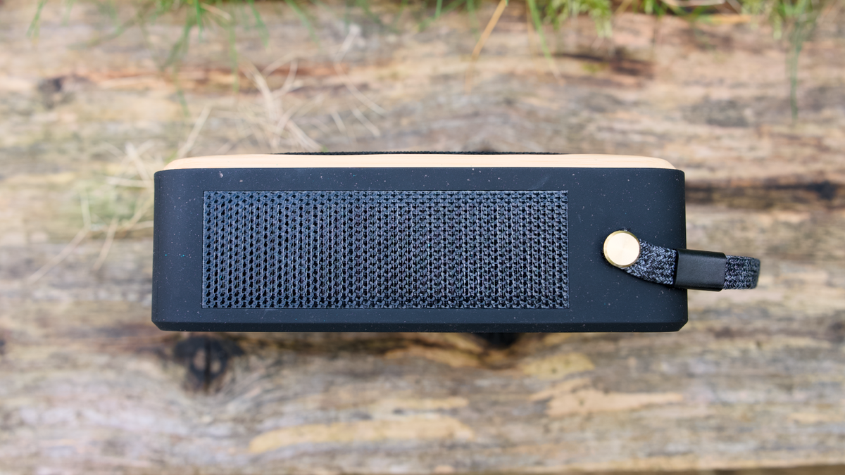 House of Marley Roots Solar Bluetooth speaker outdoors in a garden, on a wooden bench.