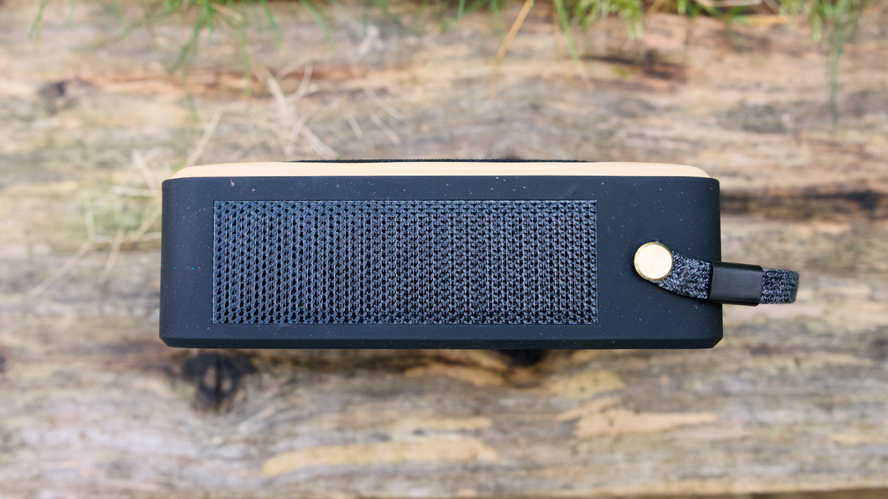 House of Marley Roots Solar Bluetooth speaker outdoors in a garden, on a wooden bench.