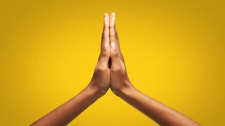 Close up of female hands clasped together in studio with yellow background