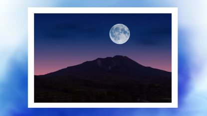 a blue moon over a mountain with a sunset on a baby blue background 