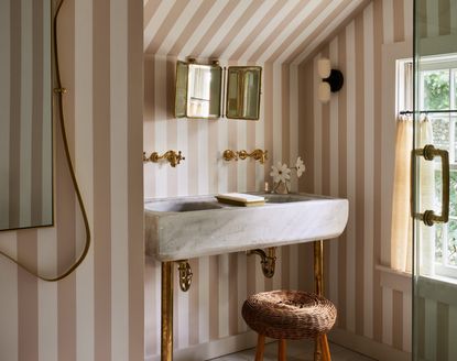 A bathroom with a pale pink striped wallpaper