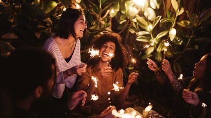 people with lit sparklers at garden party