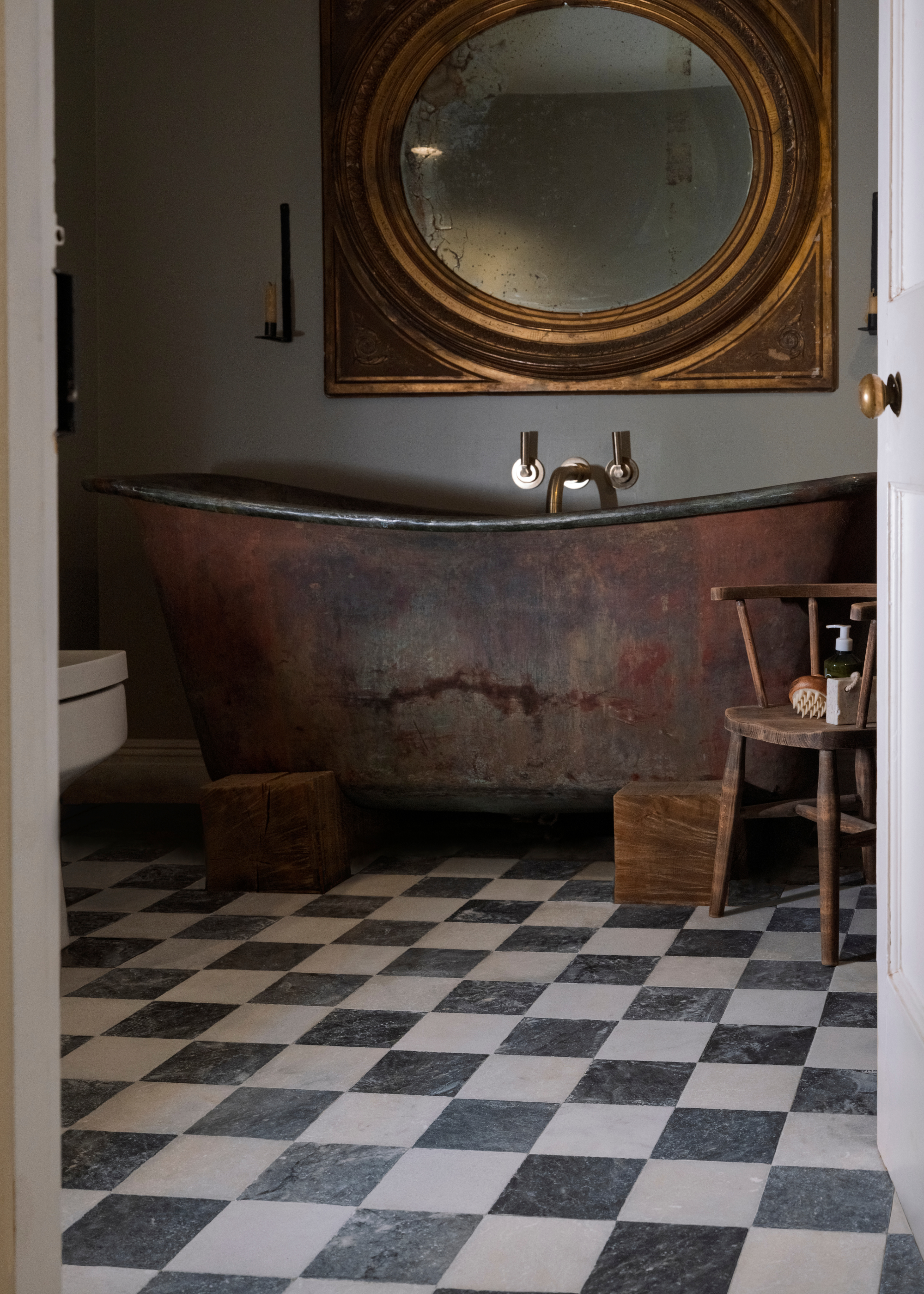 a rusty copper bath in a traditional bathroom with checkerboard tile flooring