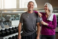 Shot of a senior married couple laughing and taking a break from their workout at the gym.