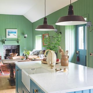 cottage kitchen with green walls and base units, blue island, open shelves and farmhouse table