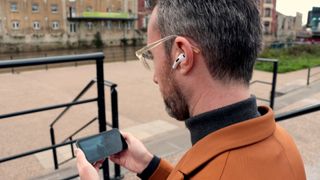 Apple AirPods 3rd Gen review, man wearing AirPods and watching film on phone