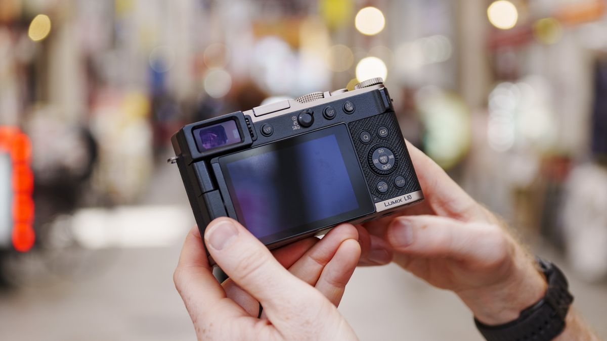 Man holding the Panasonic Lumix L10 compact camera in an urban setting of Japan