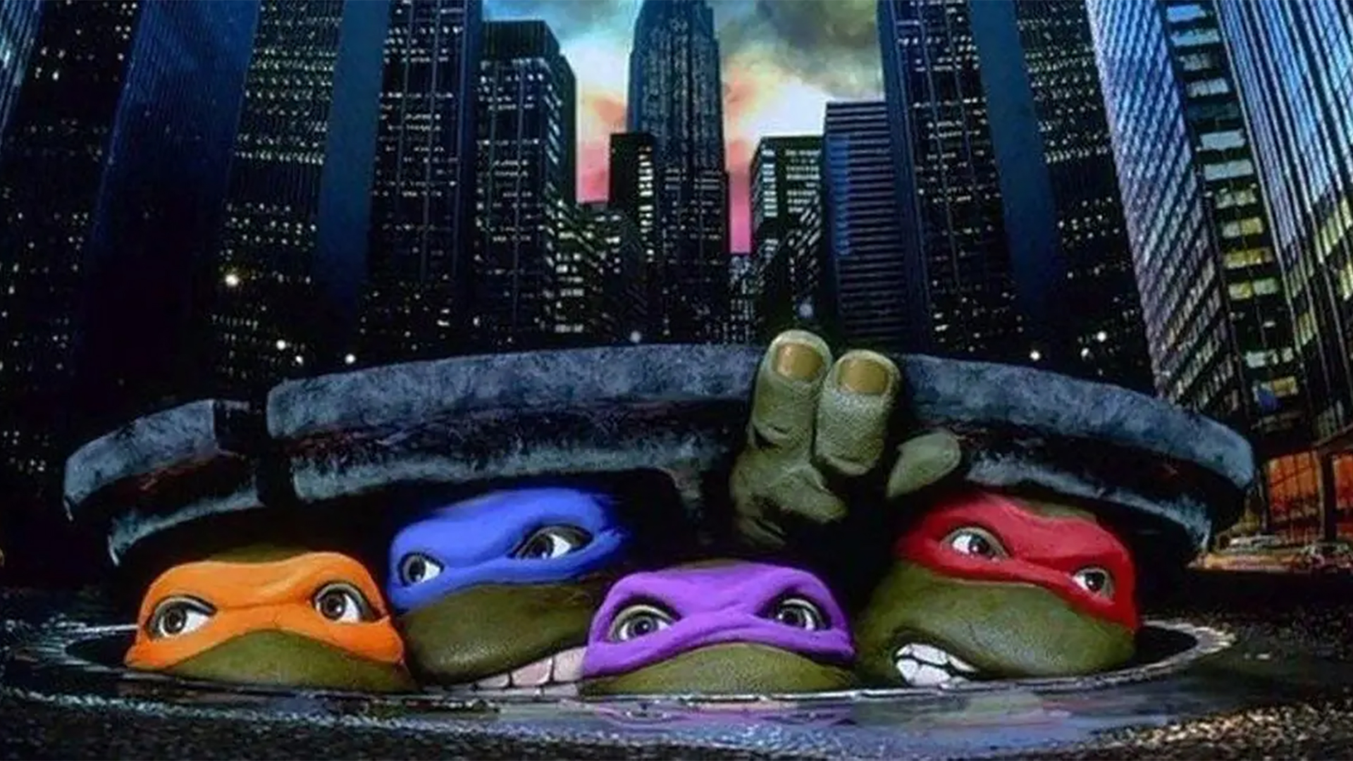 Michelangelo, Leonardo, Donatello, and Raphael peeking out from under a manhole cover