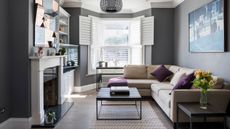 Living room makeover: grey living room with big bay window, white plantation shutters, white fireplaces and grey corner sofa