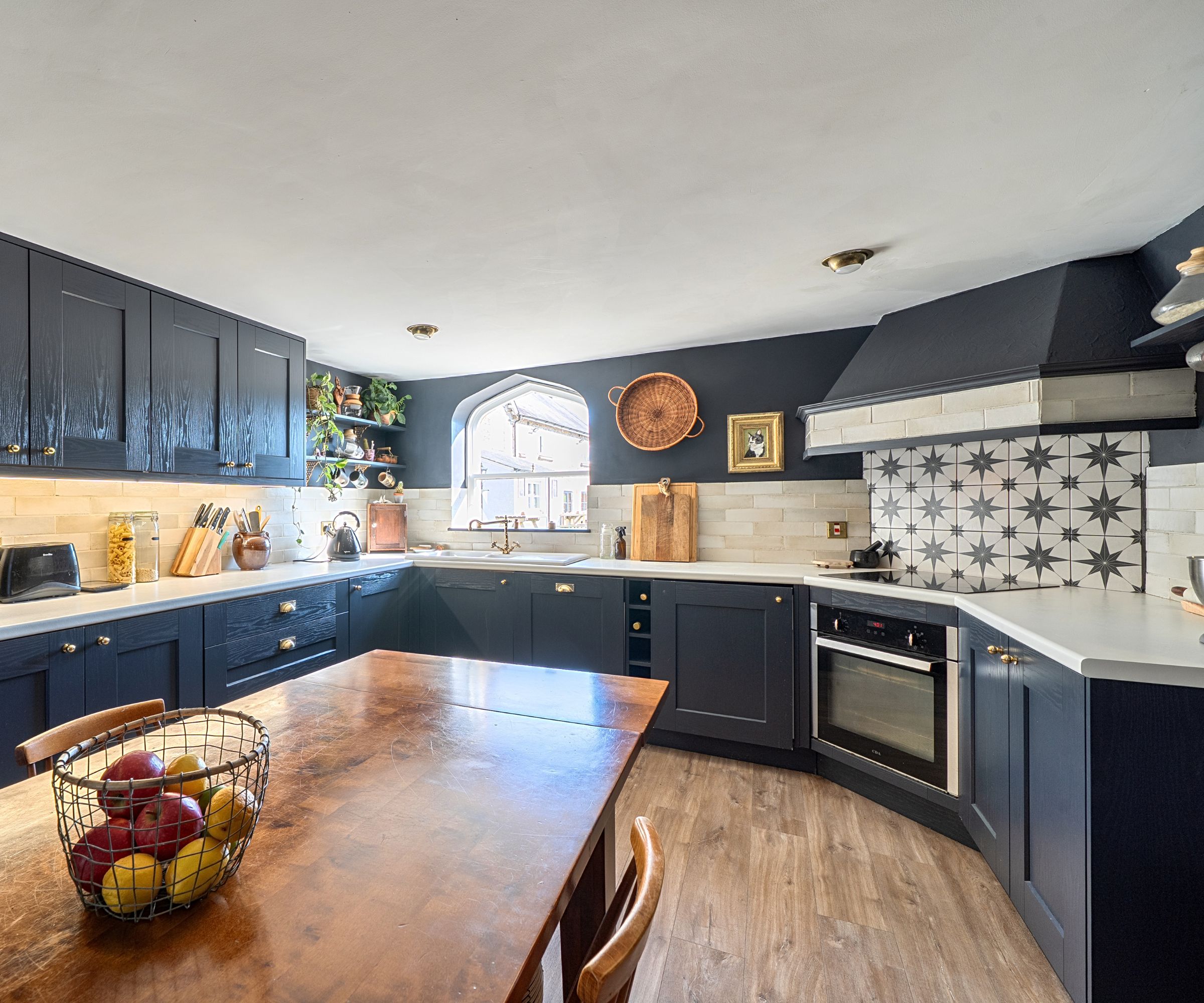 A period kitchen with star tile splashback, blue cupboards and dark blue walls