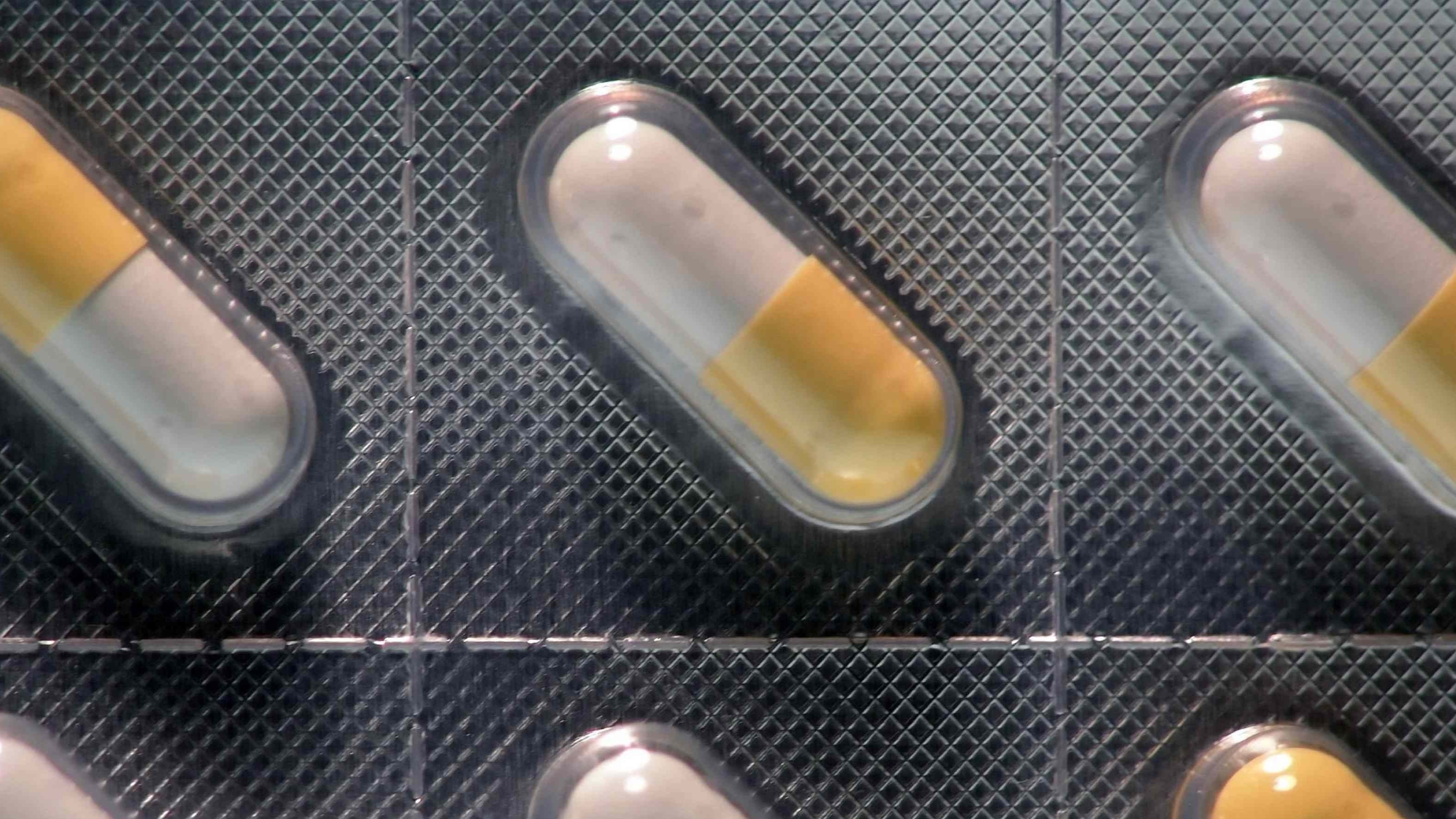 close up of yellow and white pills in silver packaging