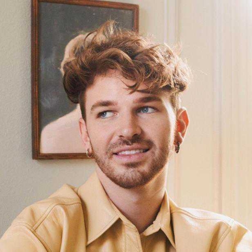Image of a man in a butter yellow, leather collared shirt.
