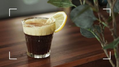Glass of black coffee with slice of lemon on the rim to demonstrate the question of does coffee and lemon help with weight loss?