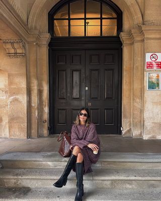 Woman wearing sweaterdress and tall black boots.