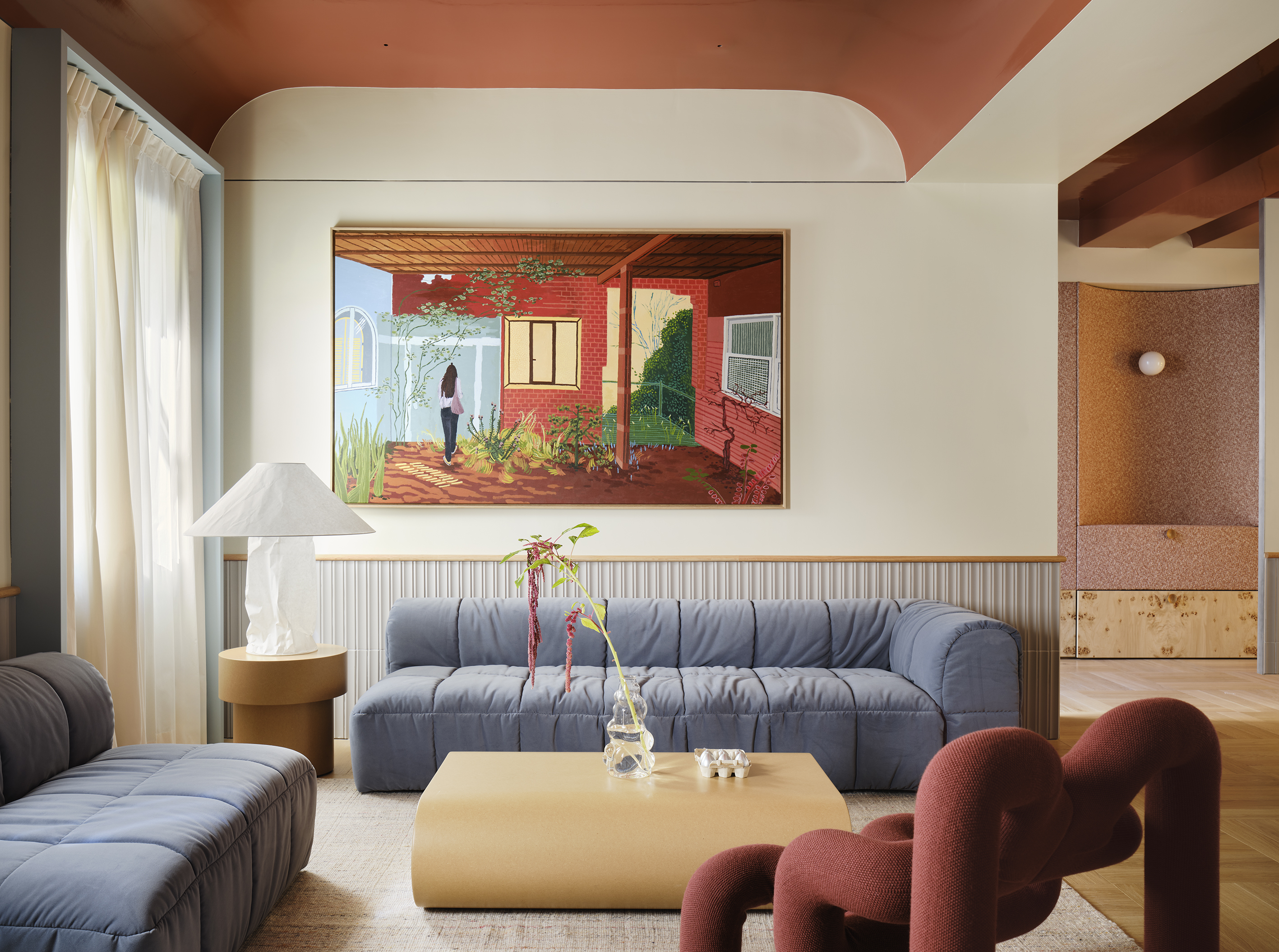 a modern living room design featuring a blue sofa, red vaulted ceiling and neutral walls