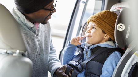 A dad putting his toddler into one of the best car seats