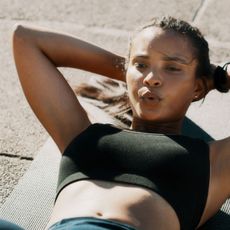 A woman trying to corkscrew method on a workout mat