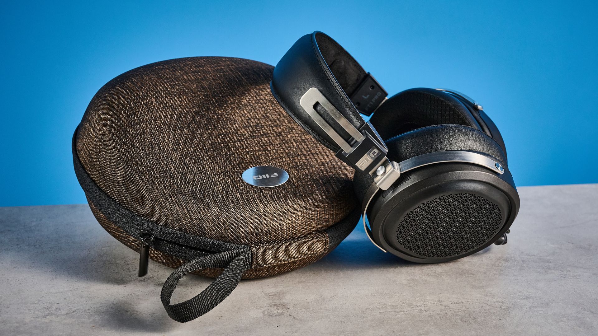 the fiio ft1 pro wired open-back headphones photographed with a blue tom's guide background