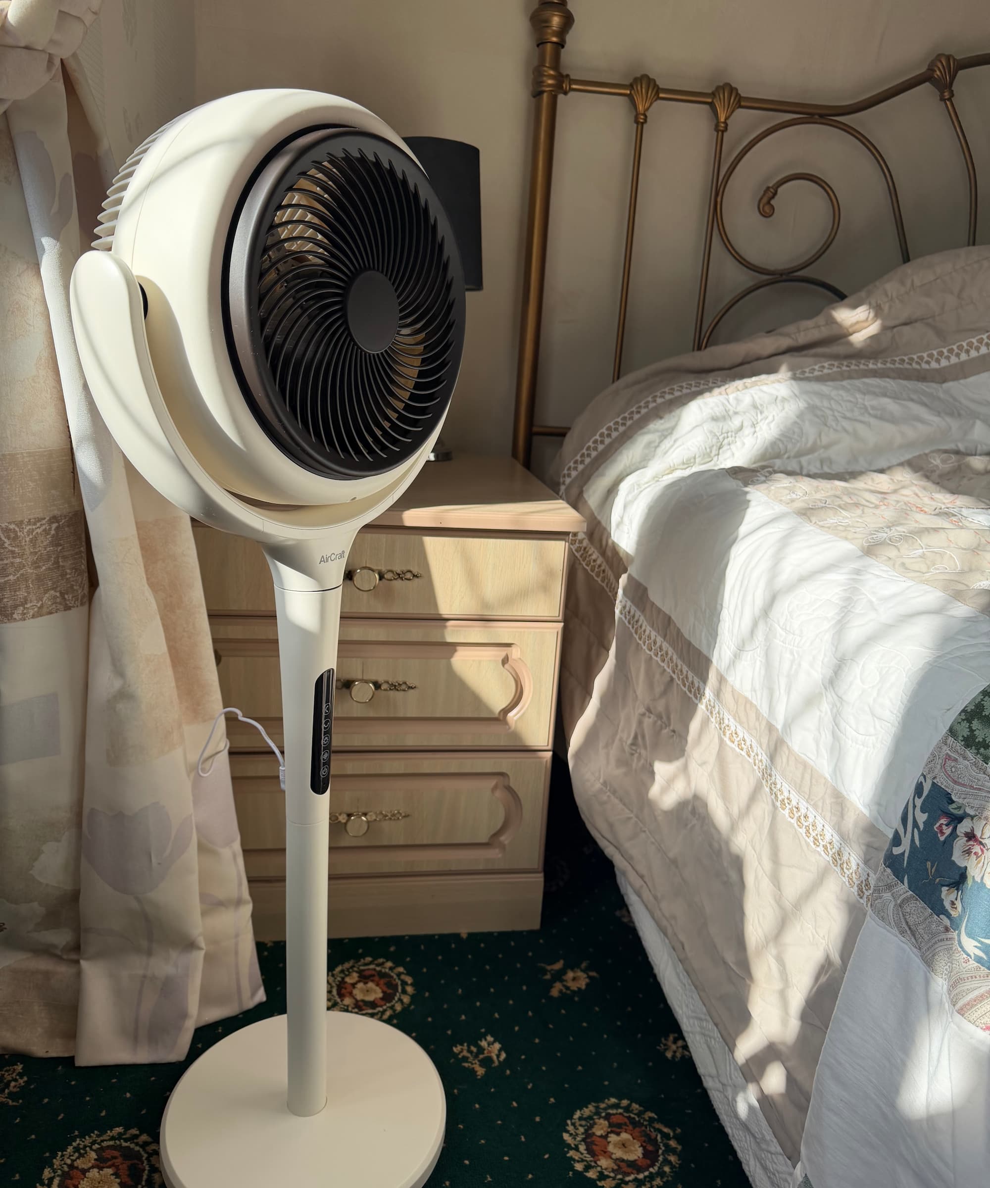 An air circulator next to a bed