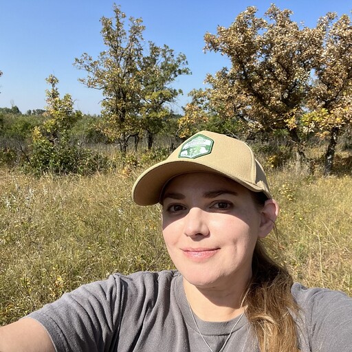 young woman wearing baseball cap outside in natural setting