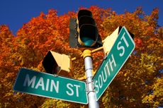 Main street sign on corner with South with autumn leaves in the background against a blue sky.