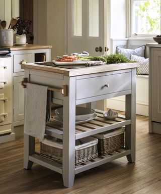 small rectangular painted pale grey kitchen island with drawer rail and slatted wooden shelving below