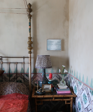 bedroom with art on wall and bedside table with lamp and vase of flowers