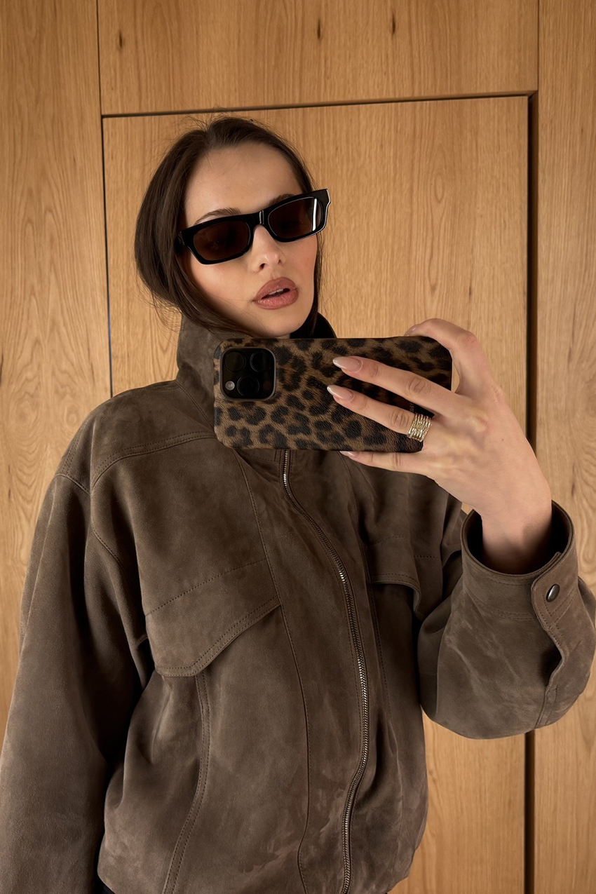 a woman wearing a brown sunglasses and brown suede jacket