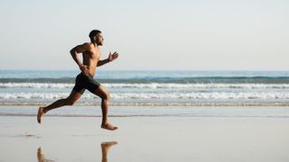 Man running barefoot on beach