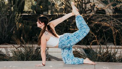 Woman performing tiger yoga pose outdoors